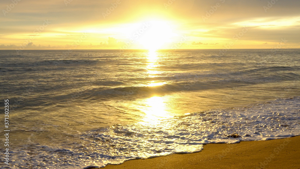 Bright sunset over the ocean with a golden sky and reflections on water