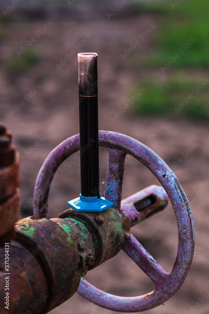 Oil sample in a test tube on an oil pump Oil sample in a test tube on an oil pump