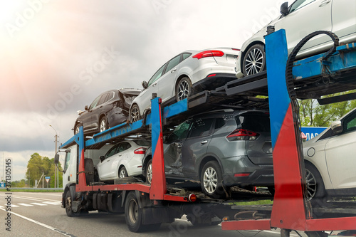 Tow truck car carrier semi trailer on highway carrying batch of damaged cars sold on insurance car auctions for repair and recovery. Vehicles shipment and rescue service © Kirill Gorlov