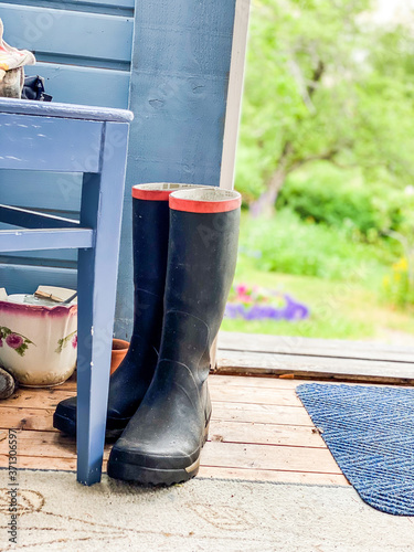 Rubber boots or wellingtons on Swedish cottage porch with green garden in the background. Nykroppa, Värmland, Sweden. photo