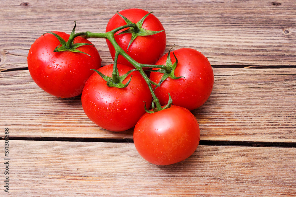 Tomatoes on the vine on rustic wooden background Tomatoes on the vine on rustic wooden background