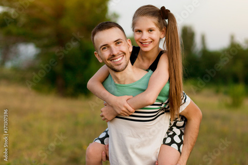 Beautiful little girl hugging embracing her father in summer