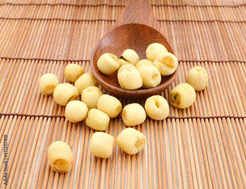 A healthy lotus nuts and wooden spoon on bamboo mat background