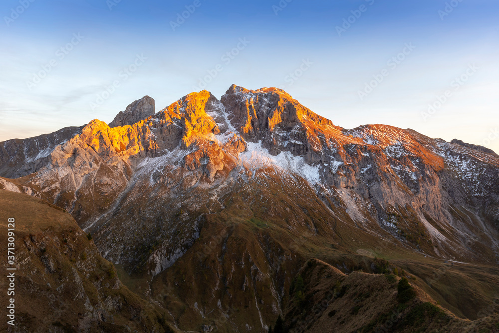 Obraz premium Italian Dolomites - view of the snow-capped peaks of the Dolomites, which are illuminated by the setting sun with a beautiful blue sky.