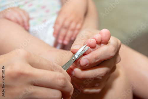 Mom cuts baby s toenails with small baby scissors. Care and guardianship of children by parents.