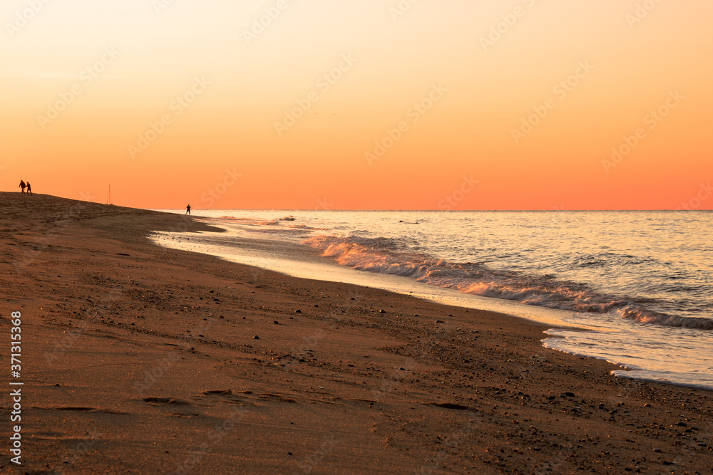 Orange sunset over a sandy beach in autumn. Cape Cod, MA, USA.