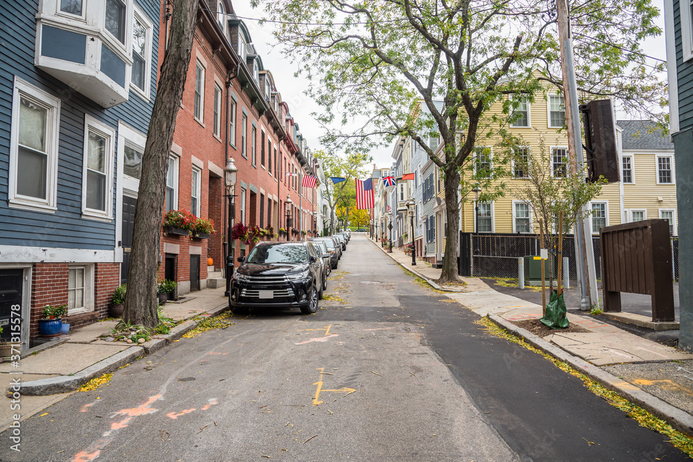 Street lined with historic brick and wooden townhouses on a cloudy autumn day