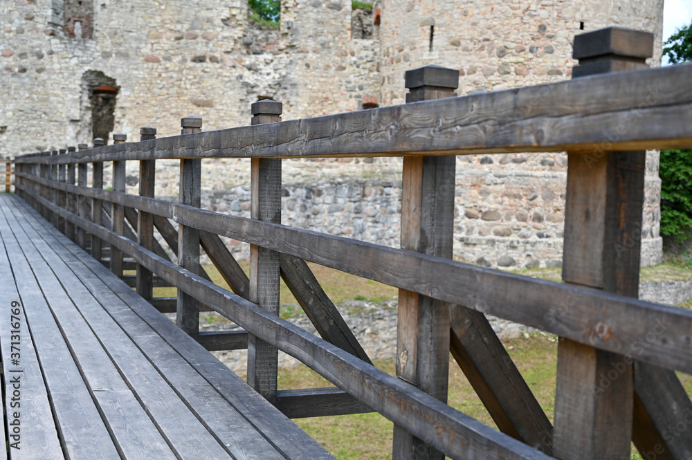 old wooden bridge over the moat to the medieval castle. Perspective view.