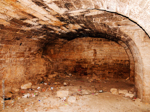 Mystic interior of an ancient dungeon. An old abandoned tunnel in an underground wine cellar. Entrance to catacombs. Dungeon An old stone fortress. As creative background for staging dark design.