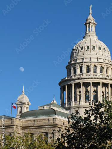 the Capitol of Texas with a three quarter moon above the State flag