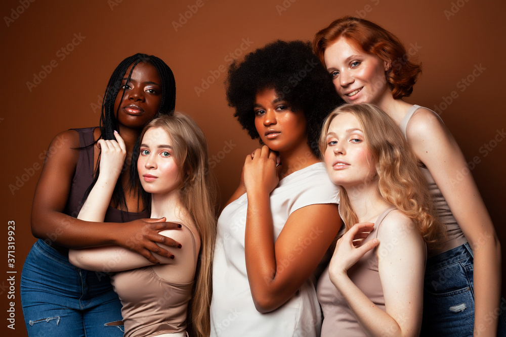 young pretty caucasian, afro, scandinavian woman posing cheerful together on brown background, lifestyle diverse nationality people concept