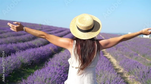 Woman in lavender flowers field at sunset in white dress and hat