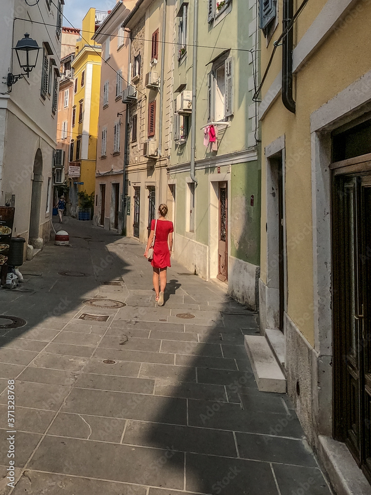 girl in red dress walking old city center of Piran, Slovenia
