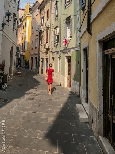 girl in red dress walking old city center of Piran, Slovenia