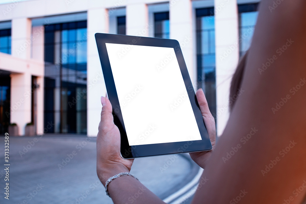 Young woman demonstrates the screen white screen tablet close-up. Mock up on the background of a modern business center.