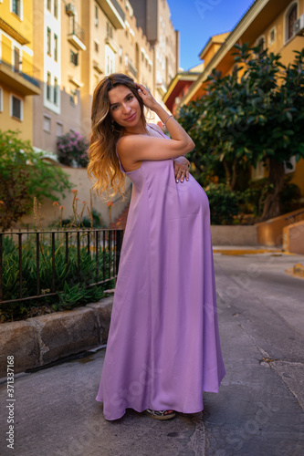 beautiful young pregnant girl in a purple dress stands in the old city © Bas
