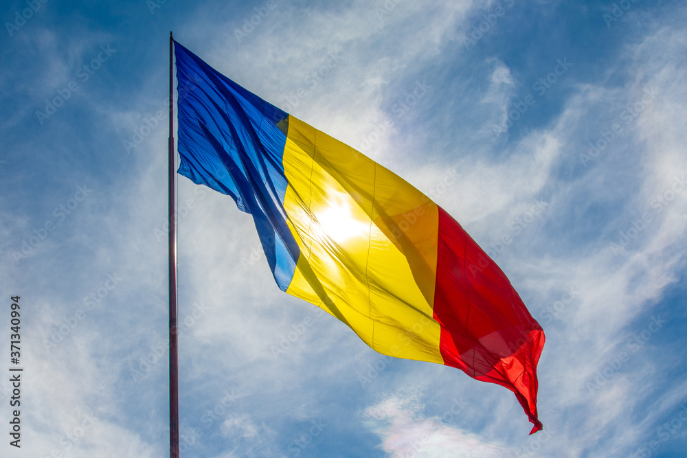 Beautiful low angle shot of the Romanian flag waving on a sunny bright sky background Beautiful low angle shot of the Romanian flag waving on a sunny bright sky background