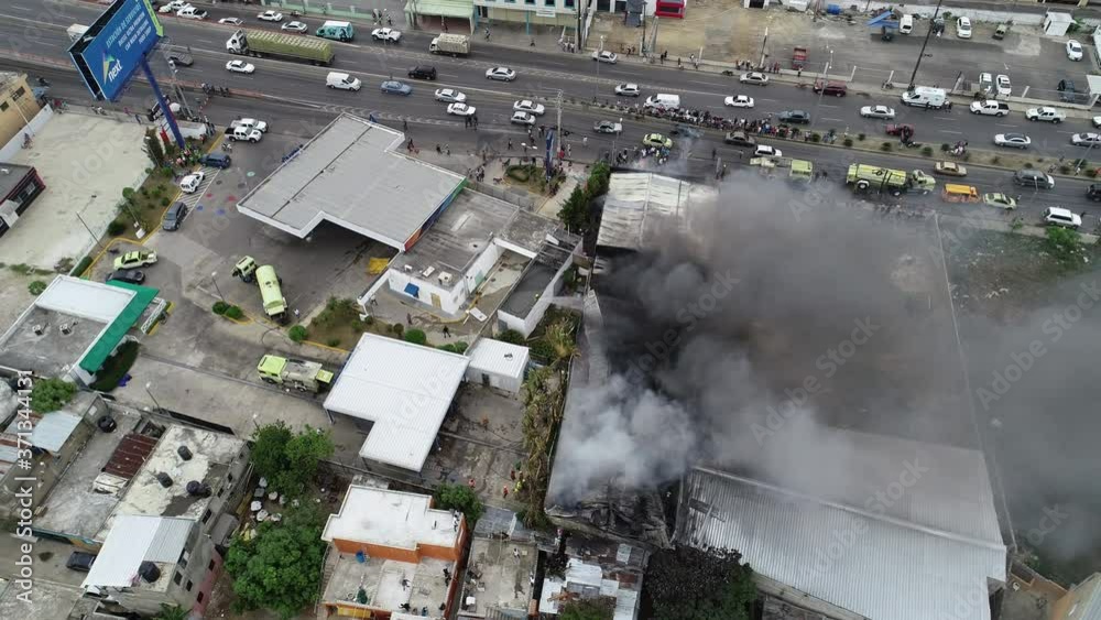 Aerial view around a building on fire, caused by a bomb, dark smoke rising, war and terror in Middle east, Asia - Orbit, drone shot