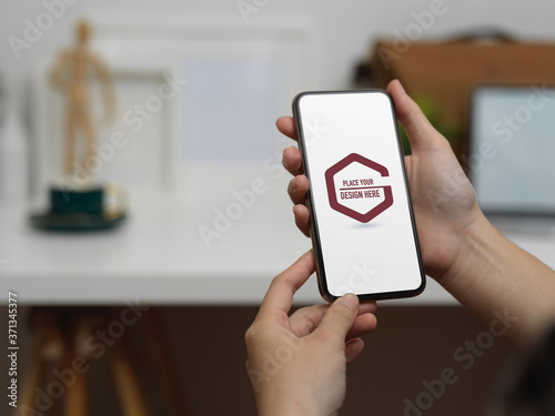 Female hands holding mock up smartphone in blurred office background