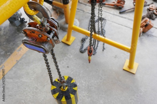 Orange color hook with chains or chain hoist hang on steel structure to wait for the Monthly inspection which is a condition of use of the industrial factory, Department of oil and gas production.