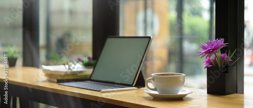 Portable workspace with mock up digital tablet, coffee cup, stationery and flower pot in cafe