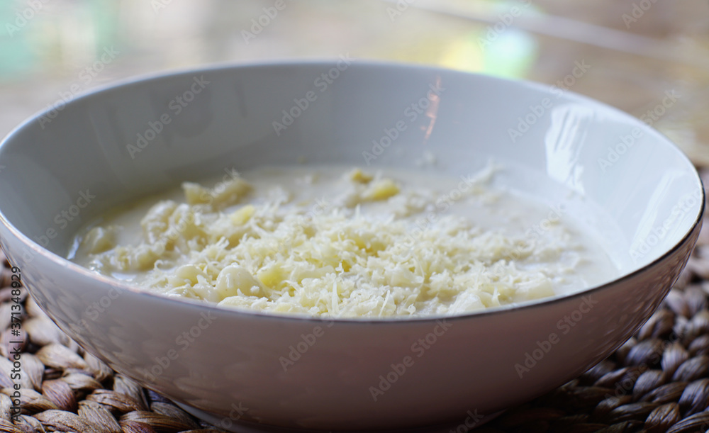 Macaroni soup with milk sauce and topped with grated cheese