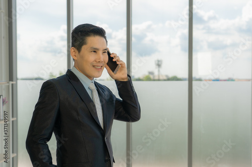 Portrait of an asian young businessman talking on the phone at the office.