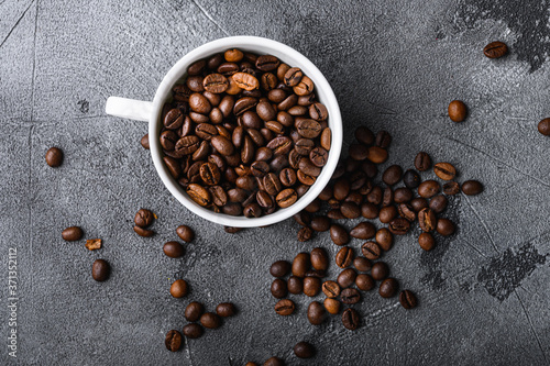Roasted coffee beans in cup on grey textured background, flat lay