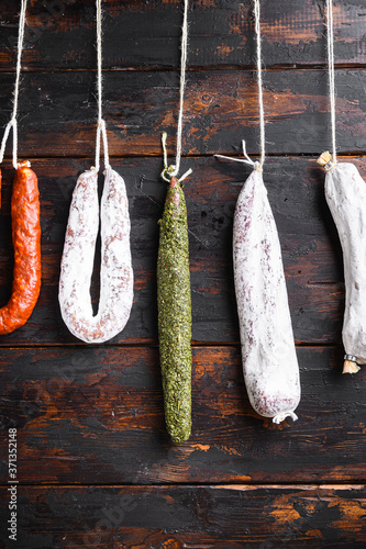 Spanish dry sausages hang from a rack at market on wooden surface