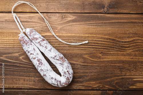 White fermented fuet sausage on light wooden background, flat lay with copy space