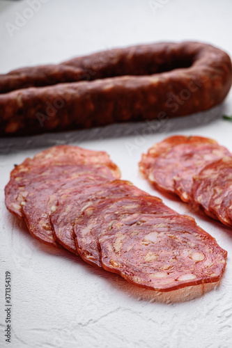 Sliced cuts of chorizo salami sausage on white textured background