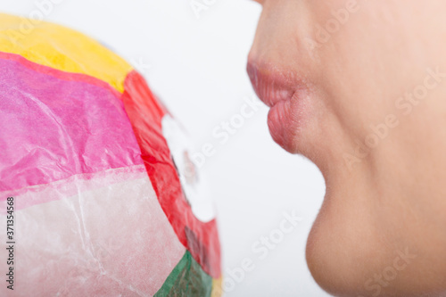 紙風船を膨らます女性の口元
