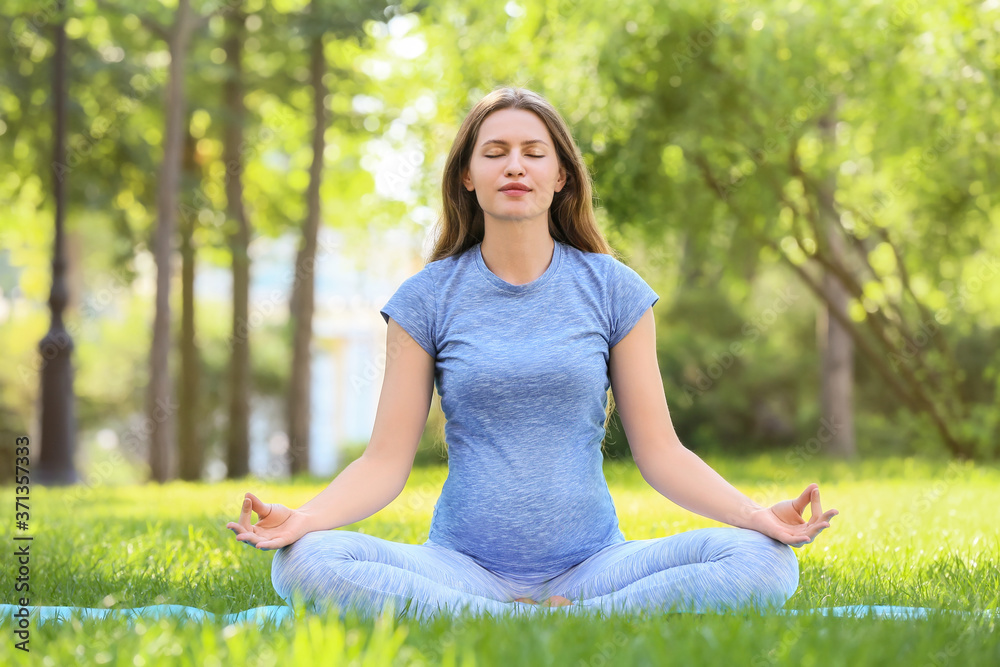 Young pregnant woman practicing yoga outdoors Young pregnant woman practicing yoga outdoors