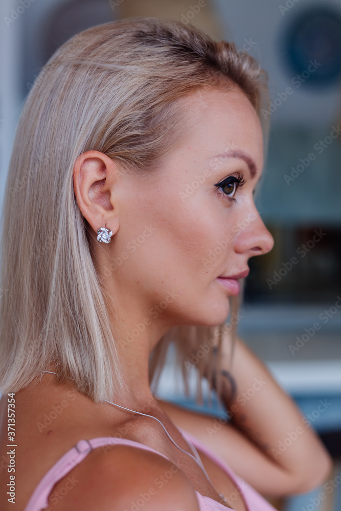 Close shot of rich luxury woman in dress  hand and ear wearing earings and ring on finger. 