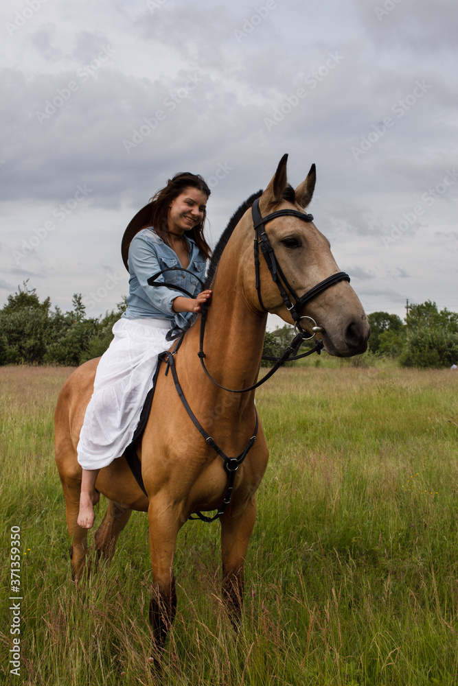 Young cow girl walking horse in green field. People and animal portrait. Horseback riding view. Active weekend Young cow girl walking horse in green field. People and animal portrait. Horseback riding view. Active weekend