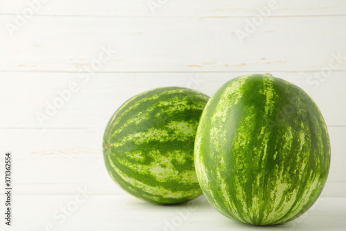 Two fresh watermelon on the white wooden background.