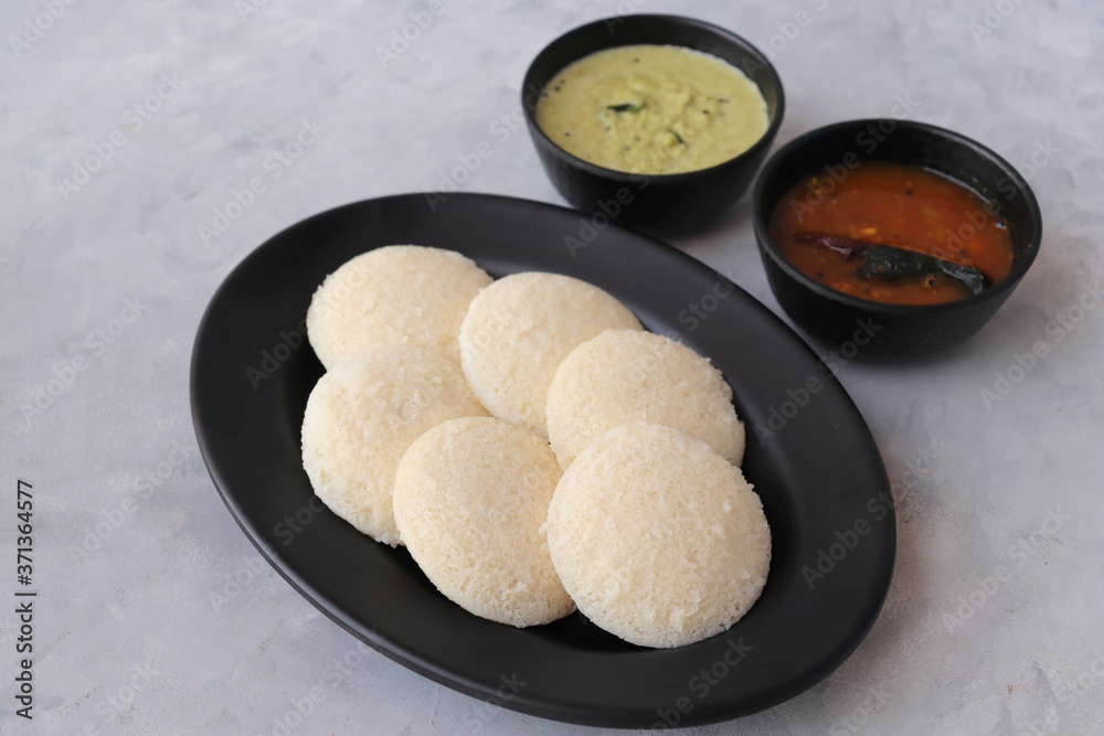 South Indian breakfast dish Idli with Coconut Chutney and sambar. Idly sambar. over light background with copy space. South Indian breakfast dish Idli with Coconut Chutney and sambar. Idly sambar. over light background with copy space.