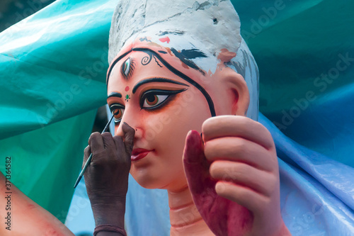 Artist creating eye of Hindu Goddess Durga with paint and brush photo