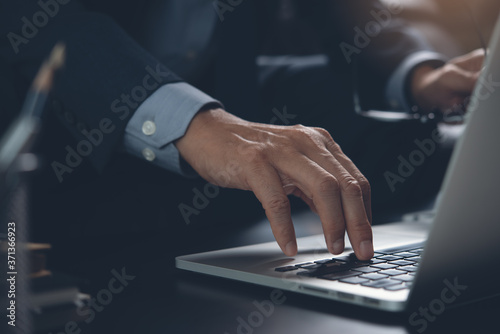 Close up of businessman hand typing on laptop computer surfing the internet while working in office