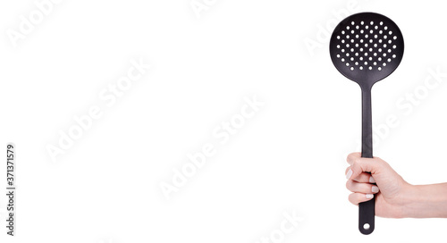 Hand with black plastic ladle, kitchen utensil. Isolated on white background, copy space template, banner.