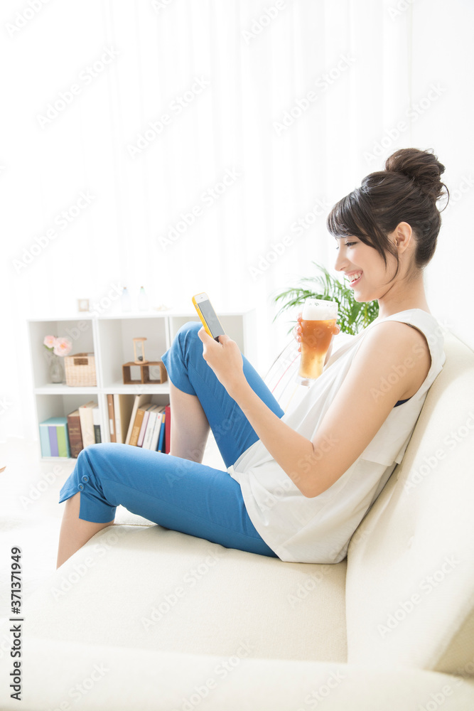 ソファに座ってスマホを見る女性 ソファに座ってスマホを見る女性
