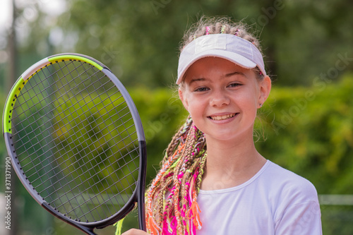Beginner girl tennis player with a tennis racket in her hands.