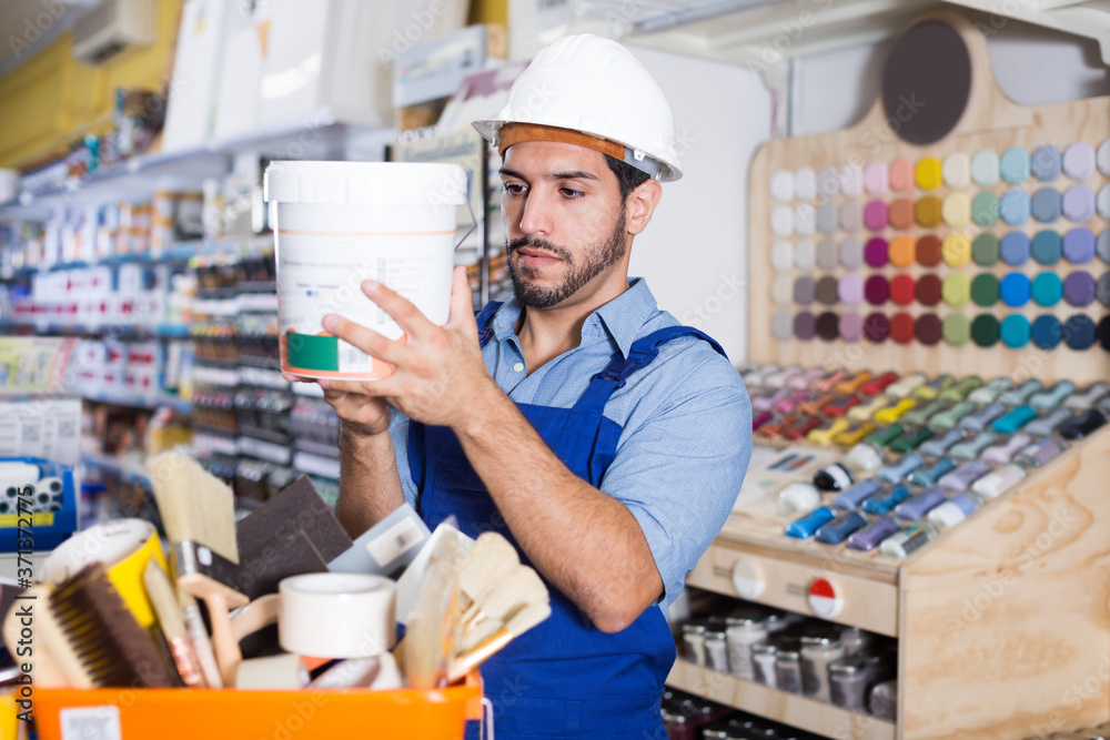 Adult workman choosing materials for renovation works in paint store