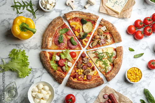 Flat lay composition with slices of different delicious pizzas on white marble table