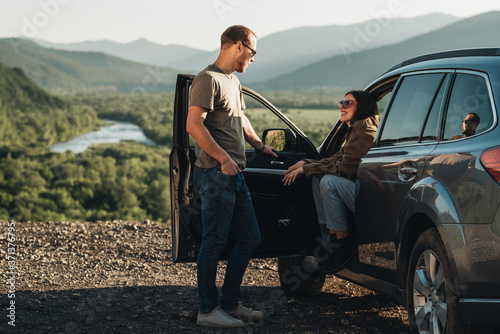 Young Traveler Couple on a Road Trip, Man and Woman Enjoying Journey on Their Car Over Beautiful Landscape