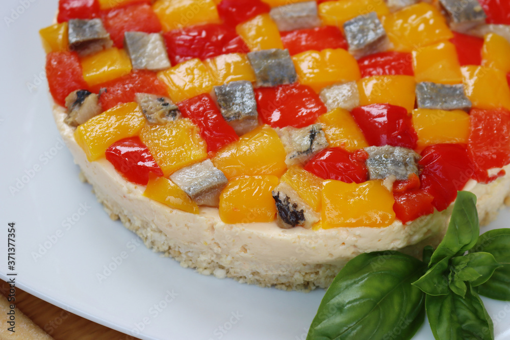 Salty cheesecake with ricotta cheese, red and yellow peppers and mackerel fish and basil on a plate on a wooden table
Salty cheesecake with ricotta cheese, red and yellow peppers and mackerel fish and basil on a plate on a wooden table