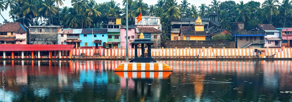 Gokarna, Karnataka, Colorful indian houses, bright orange-striped temple tank on the bank of sacred lake Koti Teertha. The city is a holy pilgrimage site for Hinduists