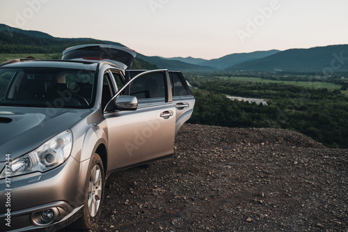 Car with Open Doors Stands on a Hill with a Beautiful View of the River and Mountains, Roadtrip Travel Concept © Romvy