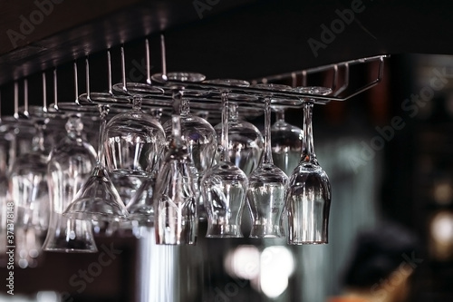 Many clean wine glasses hang beautifully in dark Asian style restaurant