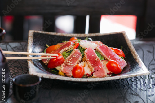 beautiful top view of a ready-made dish in a restaurant healthy ingredients fish tuna tomato greens sesame seeds photo